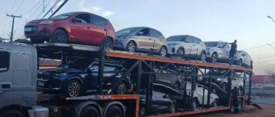 Caminhão-cegonha carregado com vários carros em uma operação logística.